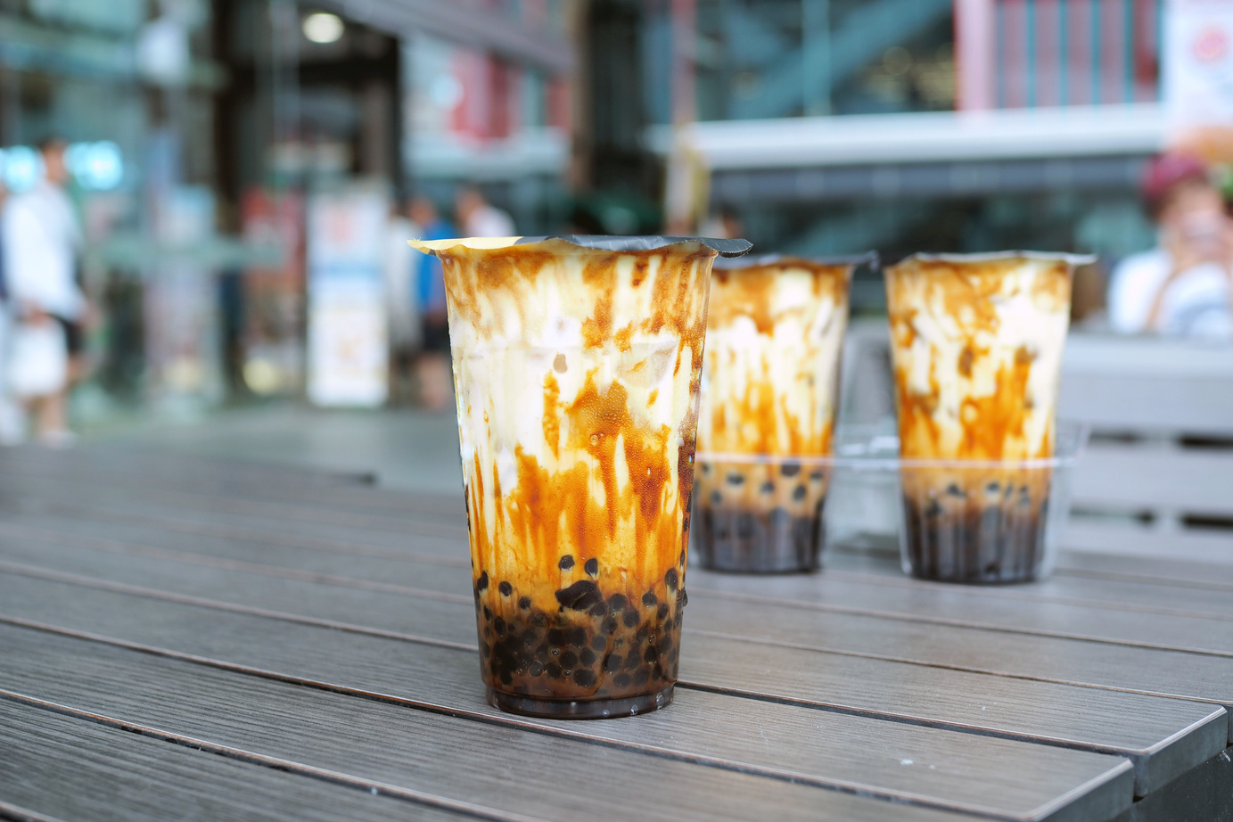 A plastic glass of refreshing iced fresh milk tea with bubble (boba) and brown sugar on table.